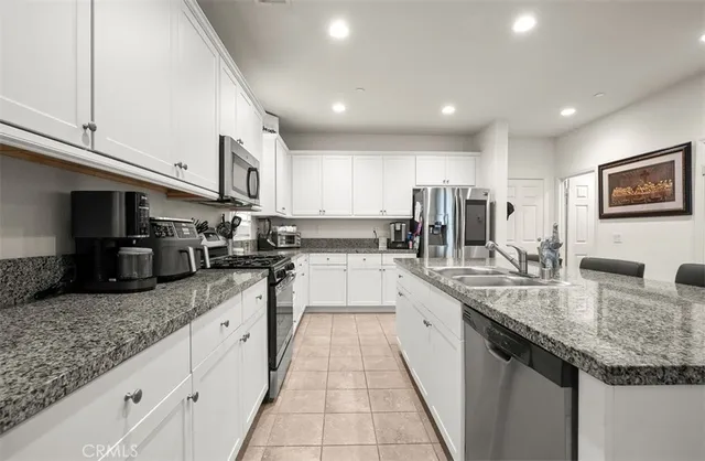 a large kitchen with granite countertop lots of counter space sink and cabinets