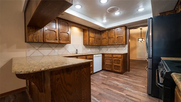 a kitchen with stainless steel appliances granite countertop a sink a stove and a wooden floors