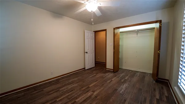 an empty room with wooden floor closet and windows