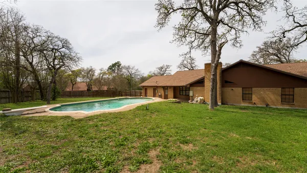 a view of a house with a big yard and large trees