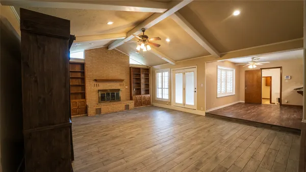 a view of empty room with wooden floor and fireplace