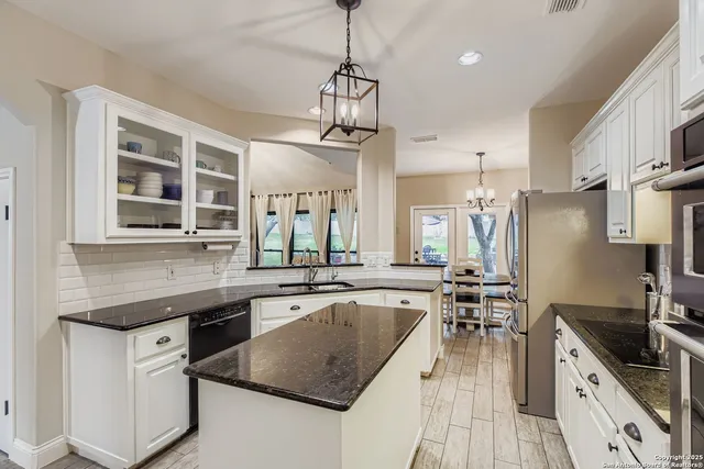 a kitchen with granite countertop a sink appliances and cabinets