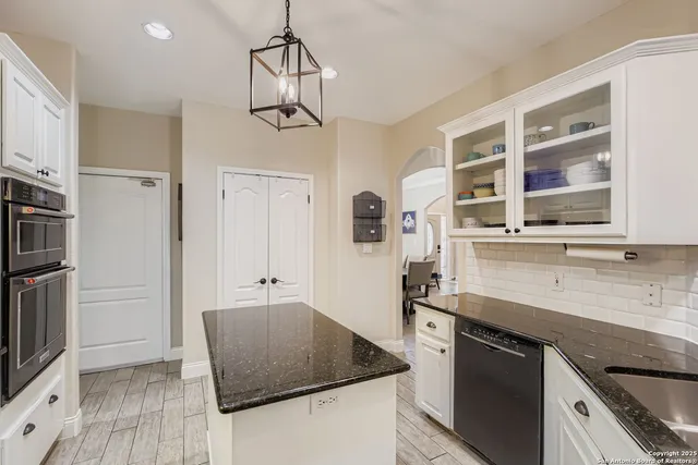 a kitchen with stainless steel appliances granite countertop a sink a stove a refrigerator a microwave oven with white cabinets and wooden floor