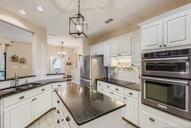 a kitchen with stainless steel appliances granite countertop a sink a stove and a refrigerator