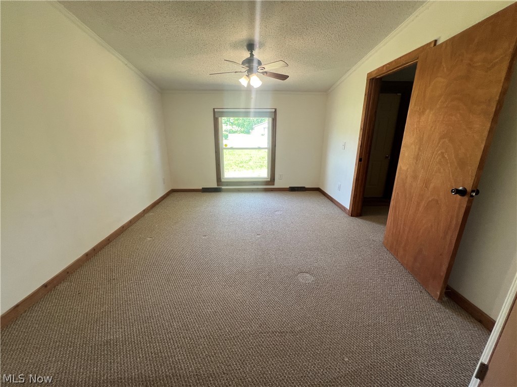 5476 Rutledge Street Southeast Dennison, OH 44621 - Photo 20 of 29 Carpeted spare room with a textured ceiling, ornamental molding, and ceiling fan
