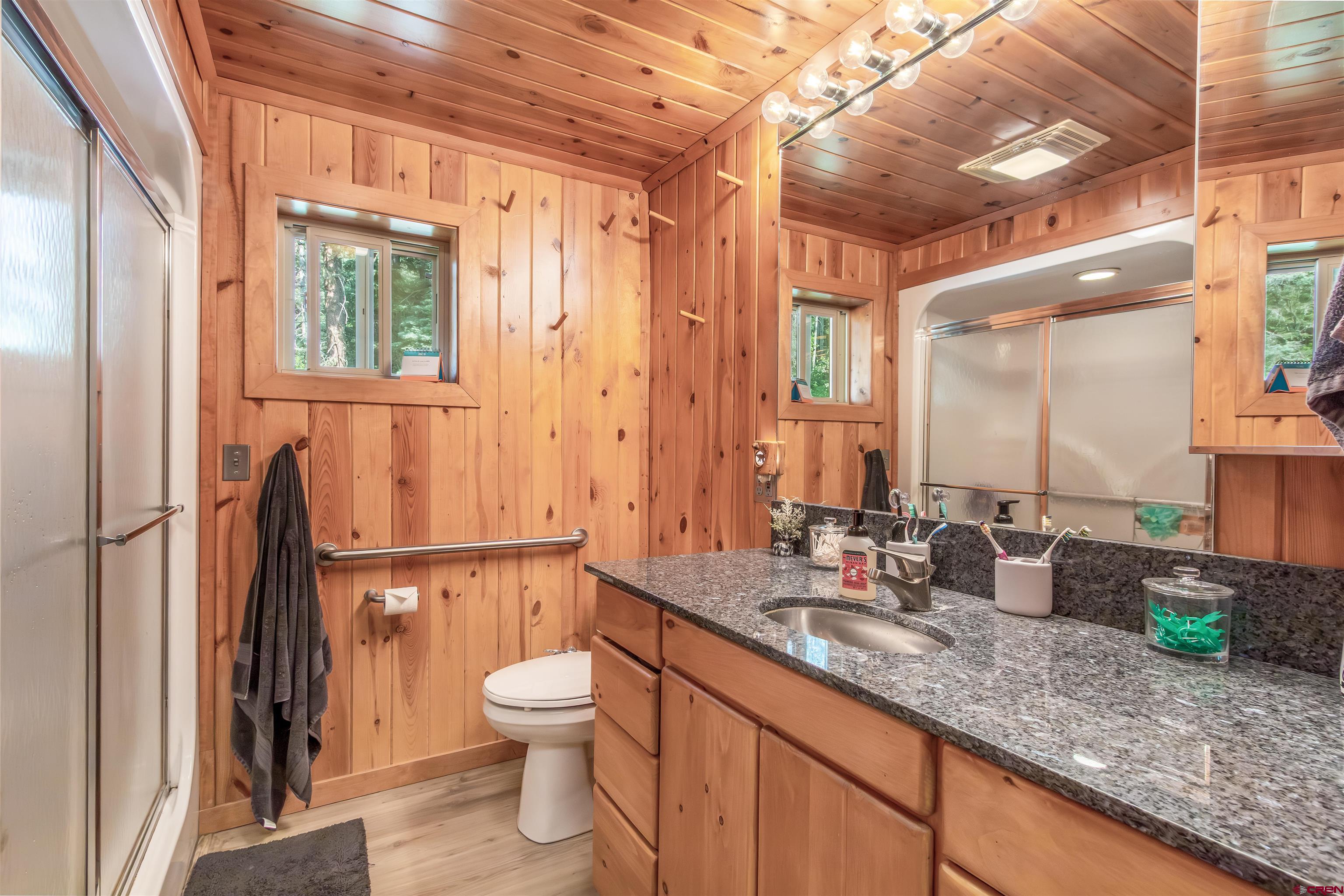 504 Weminuche Road Pagosa Springs, CO 81147 - Photo 36 of 44 a bathroom with a granite countertop sink a toilet a mirror and shower