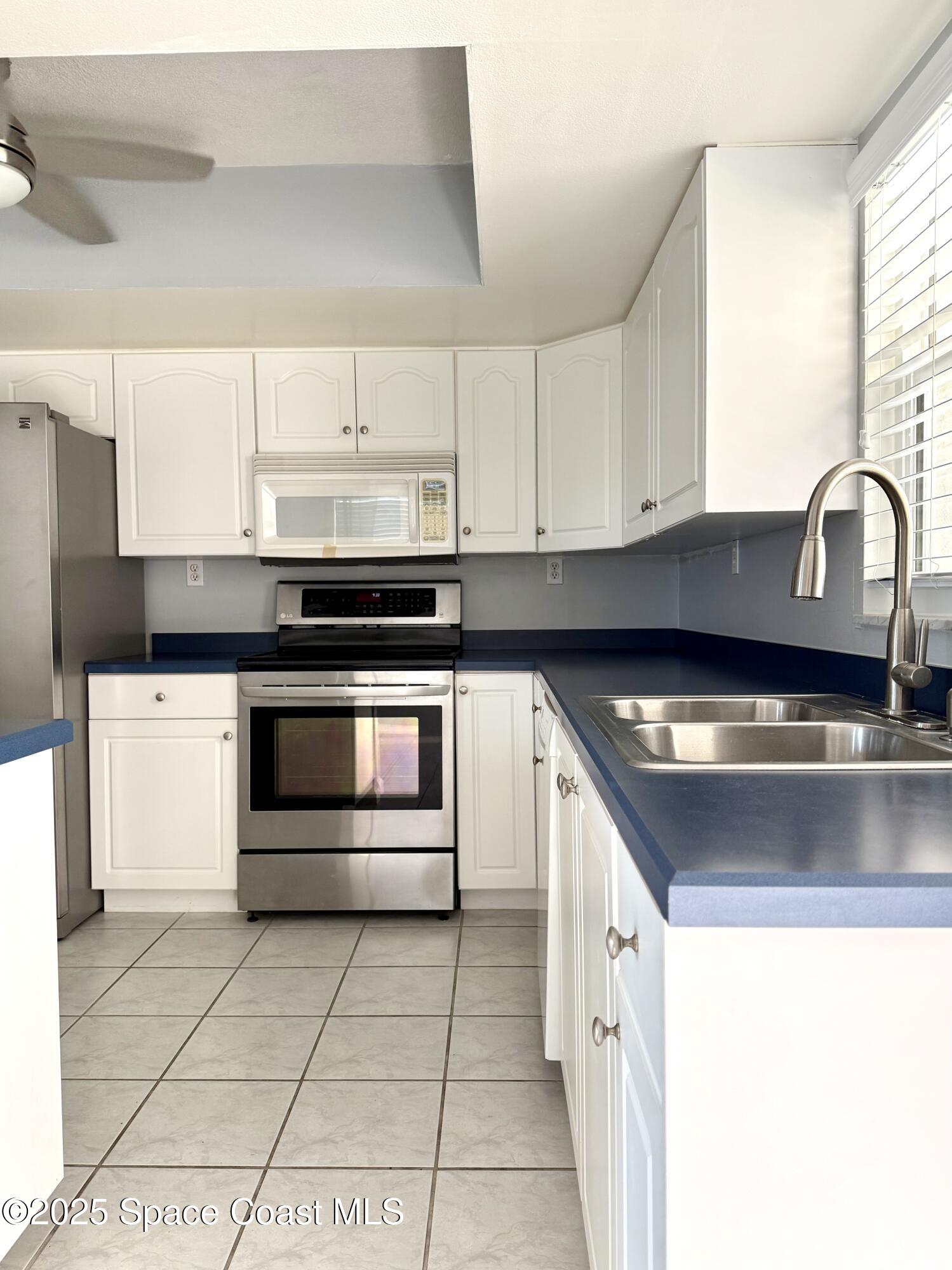 417 Ibis Lane, Unit 96 Satellite Beach, FL 32937 - Photo 10 of 29 a kitchen with stainless steel appliances granite countertop a stove a sink and a microwave