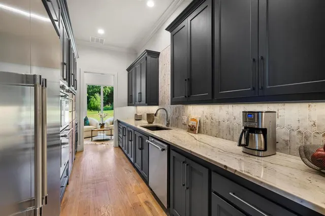 a kitchen with granite countertop a sink a counter space stainless steel appliances cabinets and a counter top space