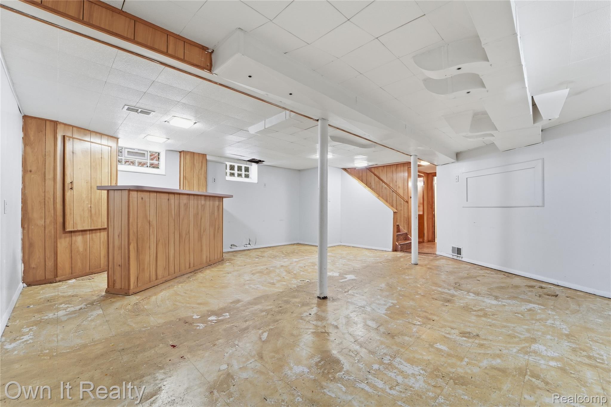 3331 Harding Street Dearborn, MI 48124 - Photo 24 of 31 Lower level featuring a built-in wood-paneled bar, wood-paneled accent wall, wood-finish stairs, and white painted walls