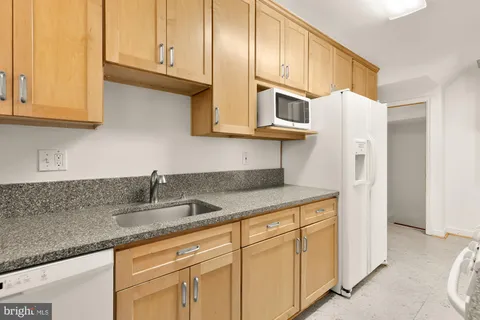 a kitchen with stainless steel appliances granite countertop a sink a refrigerator and white cabinets