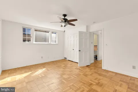 a view of empty room with wooden floor and fan