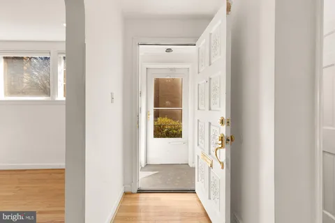 a view of a hallway with wooden floor and a bathroom