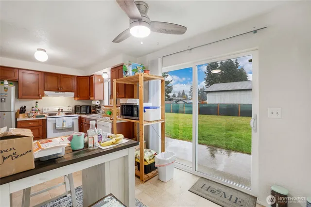 a kitchen with stainless steel appliances granite countertop a refrigerator a sink dishwasher a stove and a dining table with wooden floor