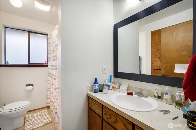 a bathroom with a granite countertop sink toilet and mirror