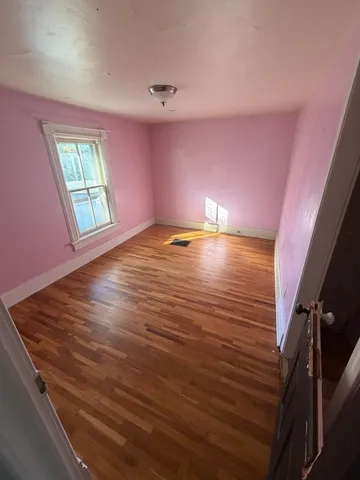 a view of an empty room with window and wooden floor