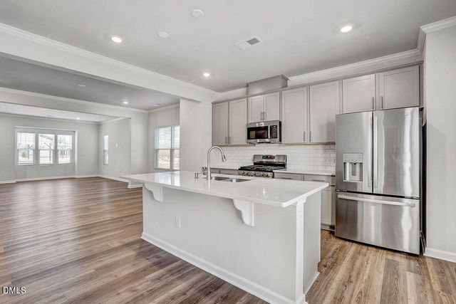 a kitchen with wooden floors white cabinets and stainless steel appliances