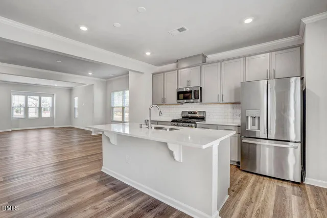 a kitchen with wooden floors white cabinets and stainless steel appliances
