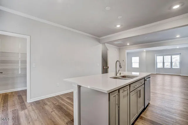 a large kitchen with stainless steel appliances granite countertop a stove top oven a sink dishwasher and a refrigerator with wooden floor