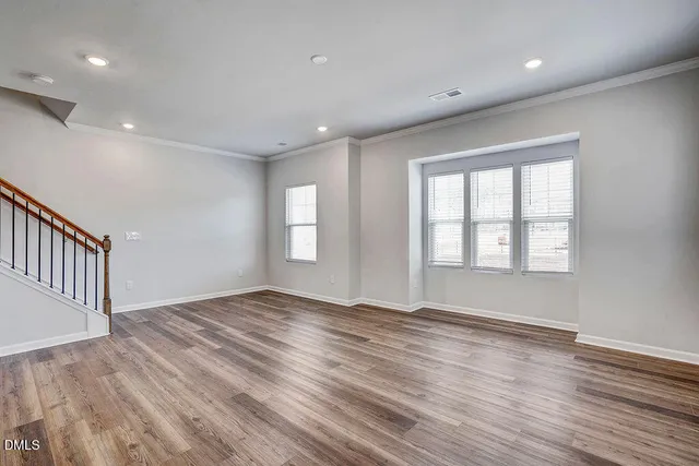 a view of an empty room with wooden floor and stairs