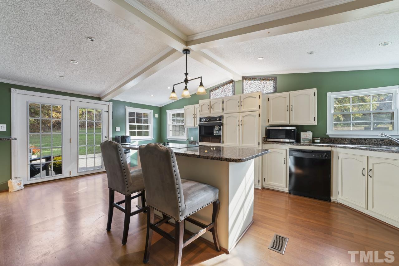 1231 Stoney Mountain Road Rougemont, NC 27572 - Photo 15 of 45 a kitchen with stainless steel appliances granite countertop a stove a refrigerator a kitchen island a dining table and chairs with wooden floor