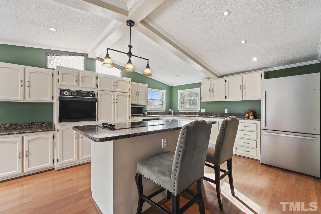1231 Stoney Mountain Road Rougemont, NC 27572 - Photo 17 of 45 a kitchen with stainless steel appliances granite countertop a stove top oven a refrigerator a sink and a dining table with white cabinets
