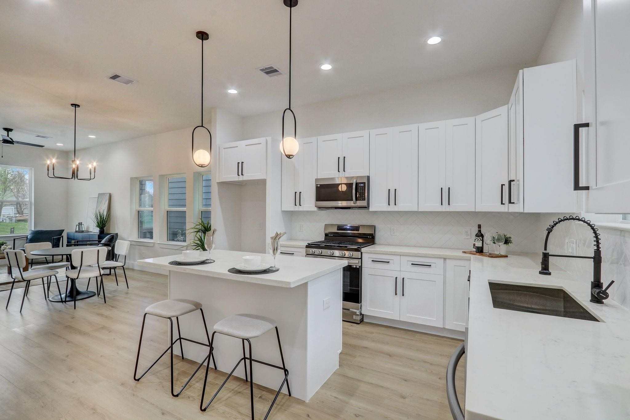 1211 Dewalt Street Houston, TX 77088 - Photo 6 of 28 a kitchen with stainless steel appliances kitchen island a white table chairs and a stove