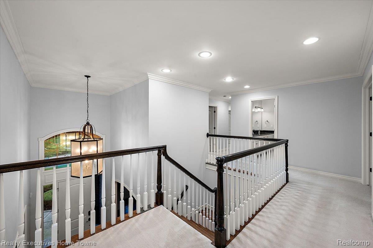 2919 North Addison Circle Rochester, MI 48306 - Photo 37 of 69 Stairway with dark wood handrails, white balusters, and a decorative pendant light fixture