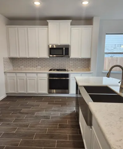a kitchen with granite countertop a sink a stove and cabinets