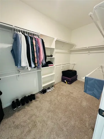 a view of walk in closet with clothes and shoes
