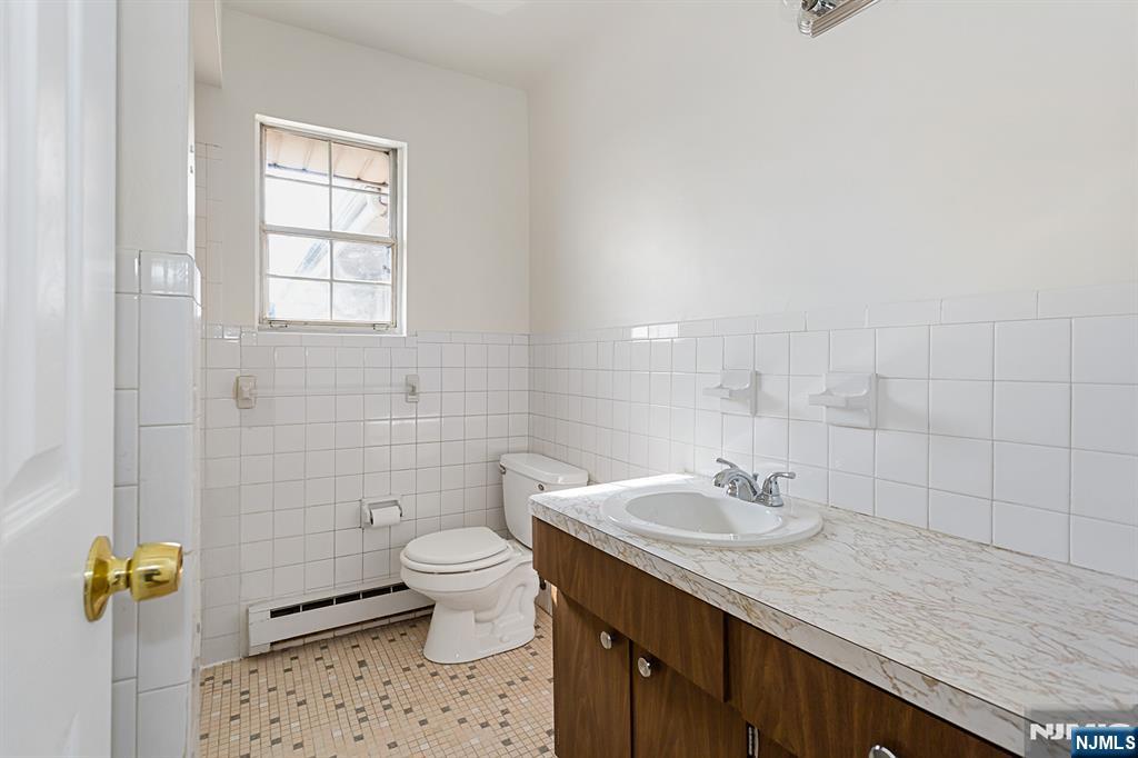 145 Arnot Street, Unit 4B Lodi, NJ 07644 - Photo 17 of 21 a bathroom with a sink a toilet and a mirror