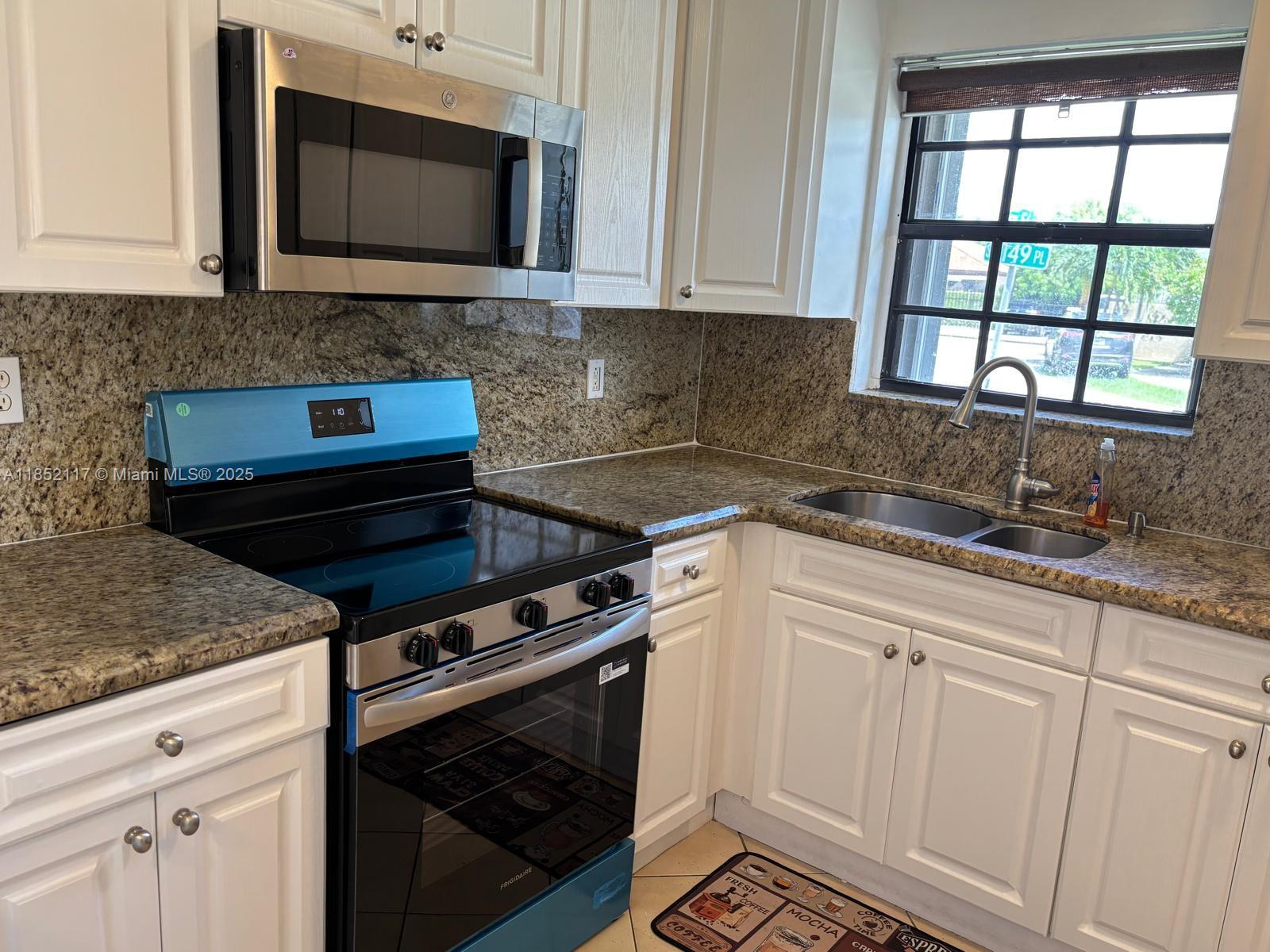 5656 Southwest 149th Place Miami, FL 33193 - Photo 7 of 28 a kitchen with granite countertop a stove microwave and sink