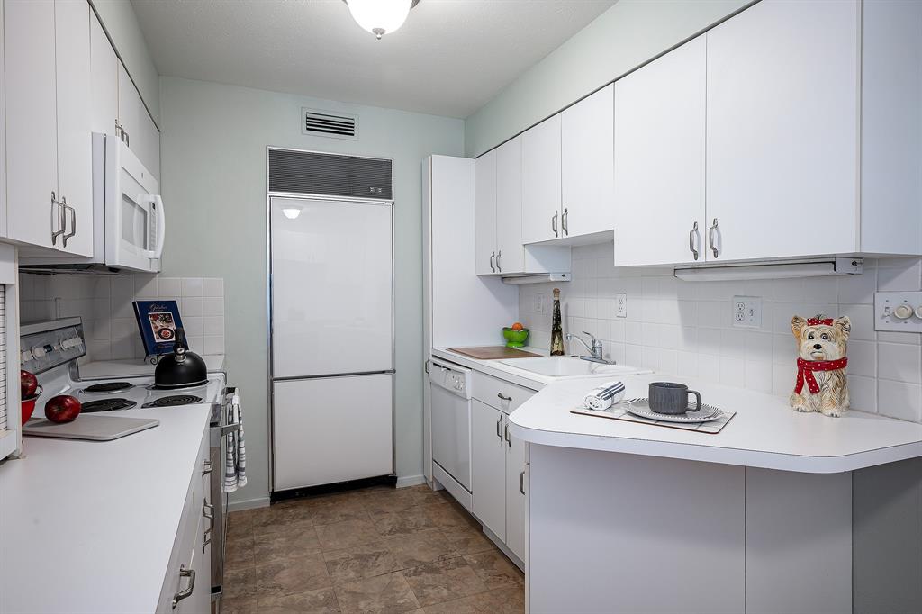 a kitchen with a refrigerator and white cabinets