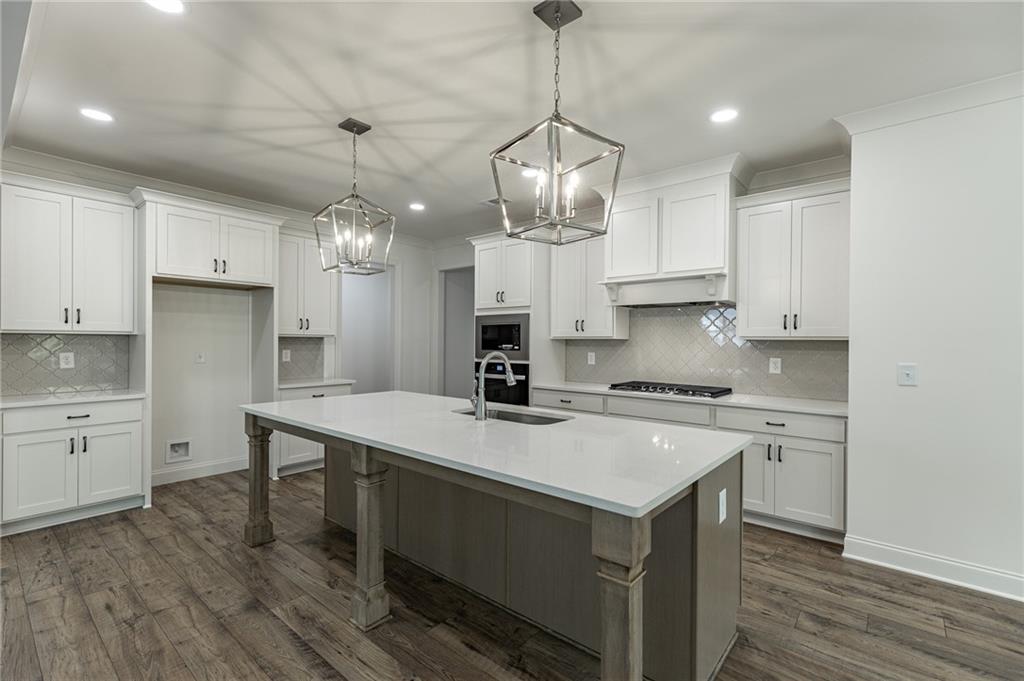 1210 Austin Road Winder, GA 30680 - Photo 15 of 56 a kitchen with a stove a chandelier and wooden cabinets
