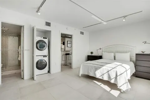a bedroom with a bed and a washing machine with racks