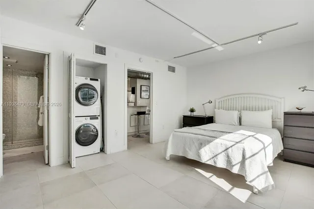 a bedroom with a bed and a washing machine with racks