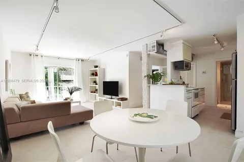 a living room with furniture a flat screen tv and kitchen view