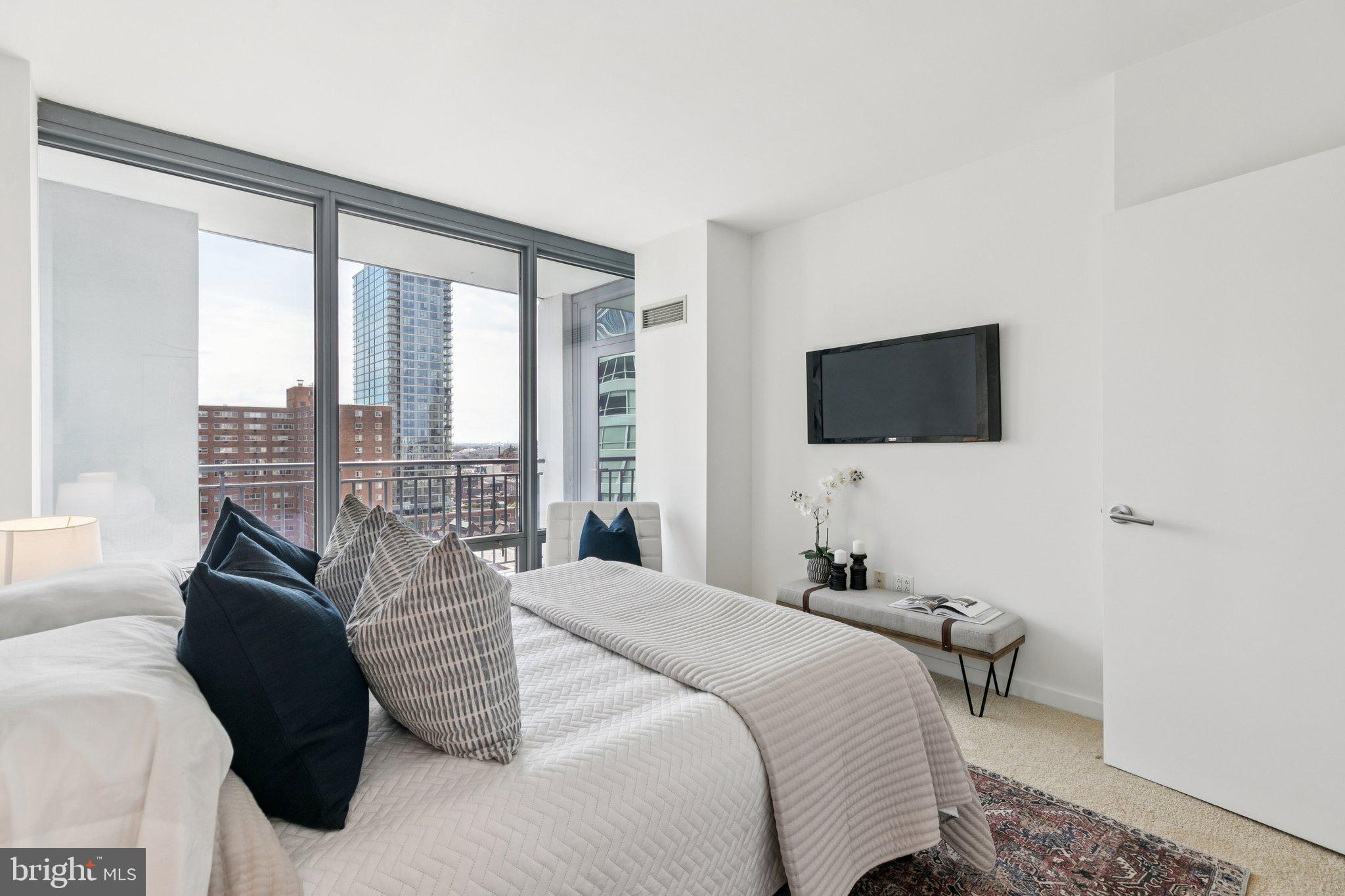 2101 Market Street, Unit 905 Philadelphia, PA 19103 - Photo 13 of 30 a bedroom with a bed and a flat tv screen next to a window