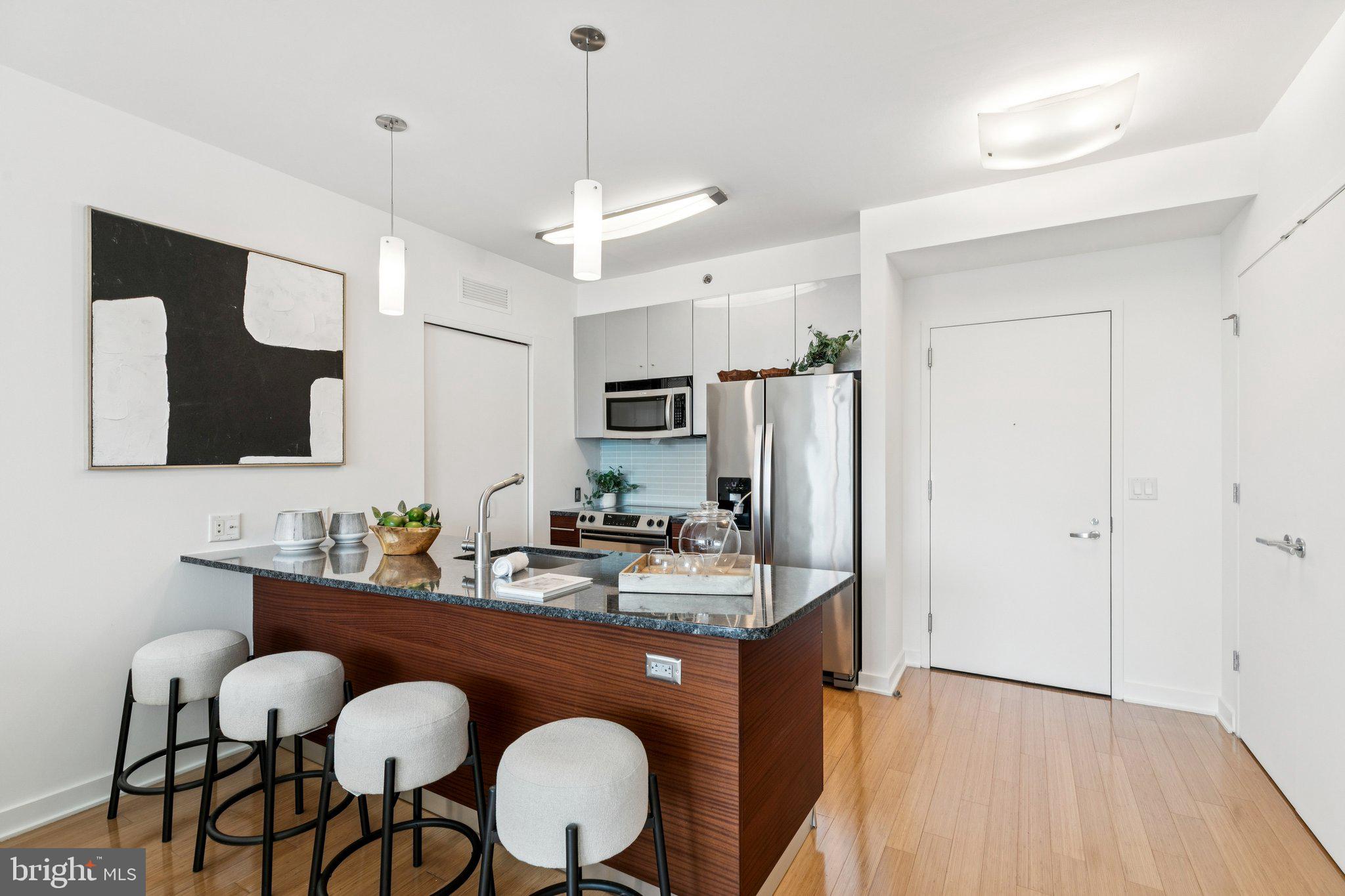2101 Market Street, Unit 905 Philadelphia, PA 19103 - Photo 8 of 30 a dining room with stainless steel appliances kitchen island granite countertop furniture a sink and a refrigerator