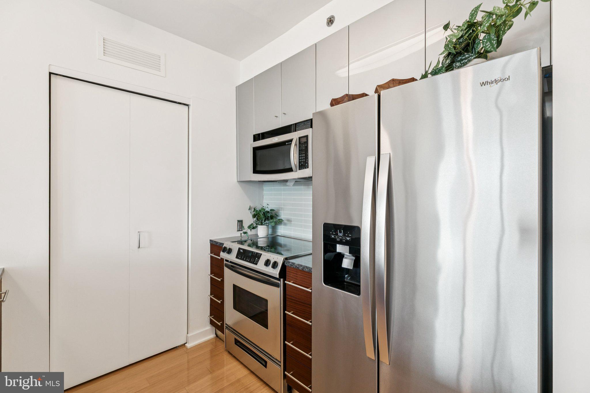2101 Market Street, Unit 905 Philadelphia, PA 19103 - Photo 10 of 30 a kitchen with stainless steel appliances a refrigerator a microwave a stove and white cabinets with wooden floor