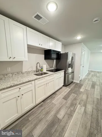 a large white kitchen with stainless steel appliances granite countertop a sink and cabinets