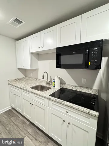 a kitchen with granite countertop white cabinets and sink