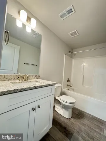 a bathroom with a granite countertop sink a toilet and a mirror
