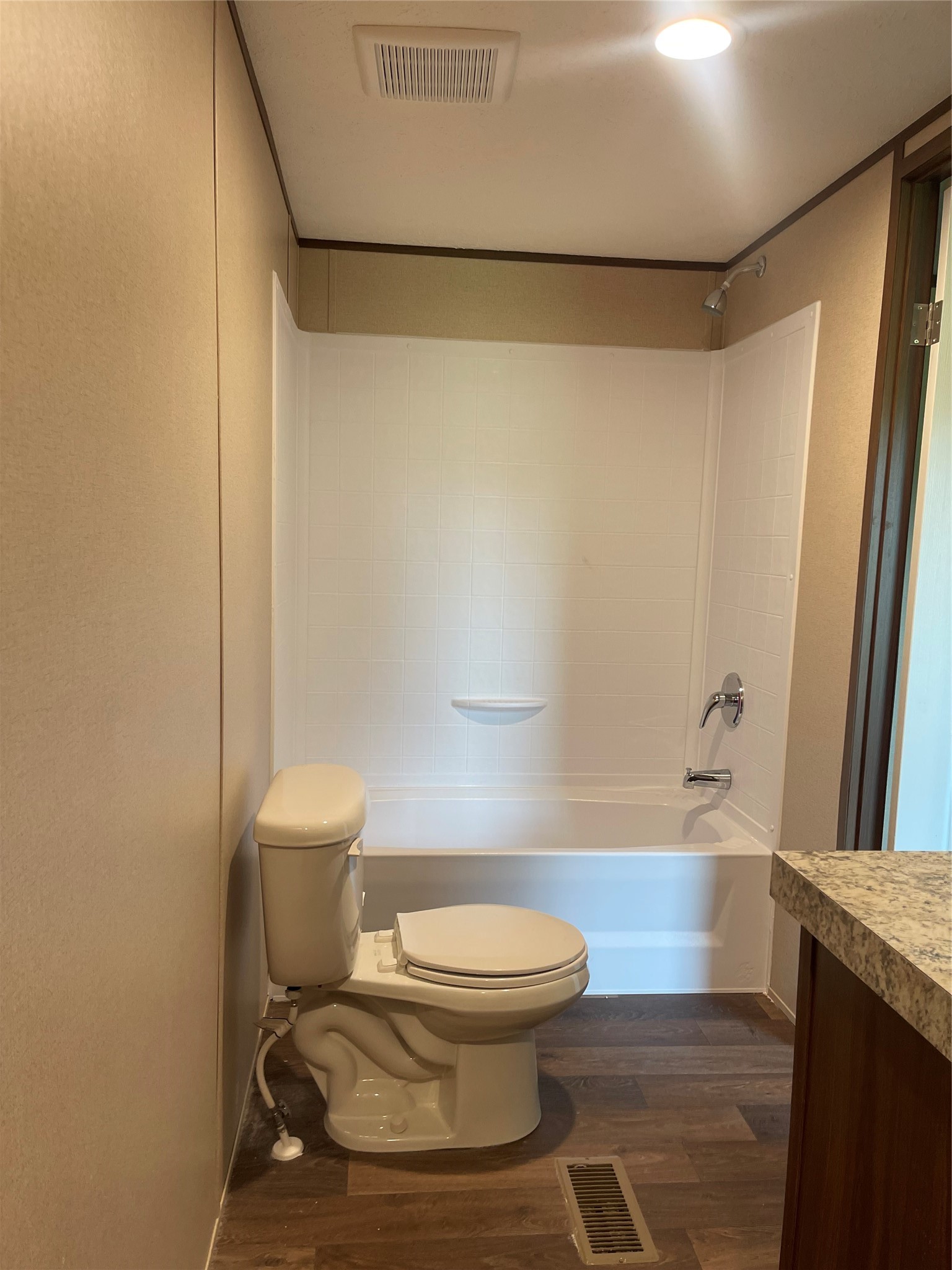 8114 McHard Road Pearland, TX 77581 - Photo 7 of 12 This bathroom features a clean, modern design with a bathtub-shower combo, neutral-toned walls, and wood-look flooring. It includes a standard toilet and a granite countertop, offering a functional and stylish space.