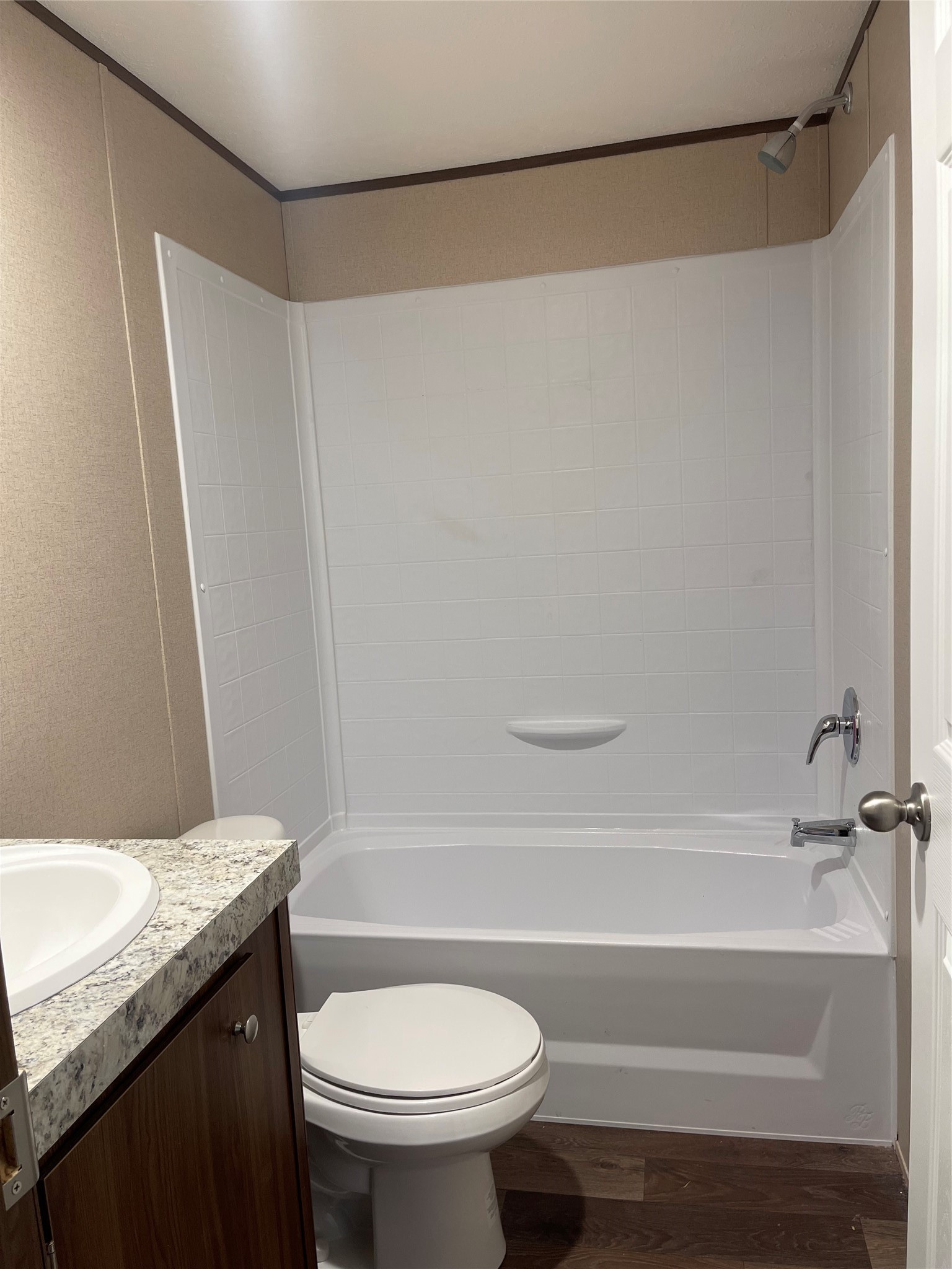 8114 McHard Road Pearland, TX 77581 - Photo 9 of 12 Compact bathroom featuring a bathtub-shower combo, single vanity with a granite-style countertop, and a toilet. Neutral tones and wood-look flooring offer a modern, clean look.