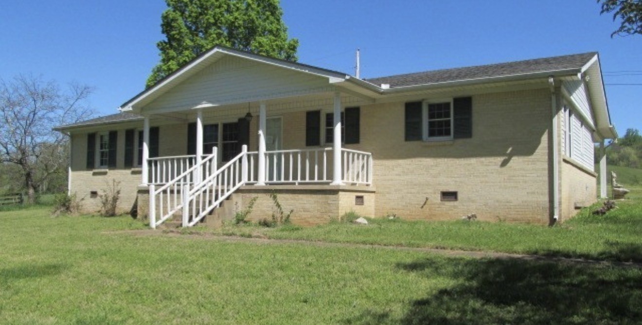 a view of a house with backyard and a tree
