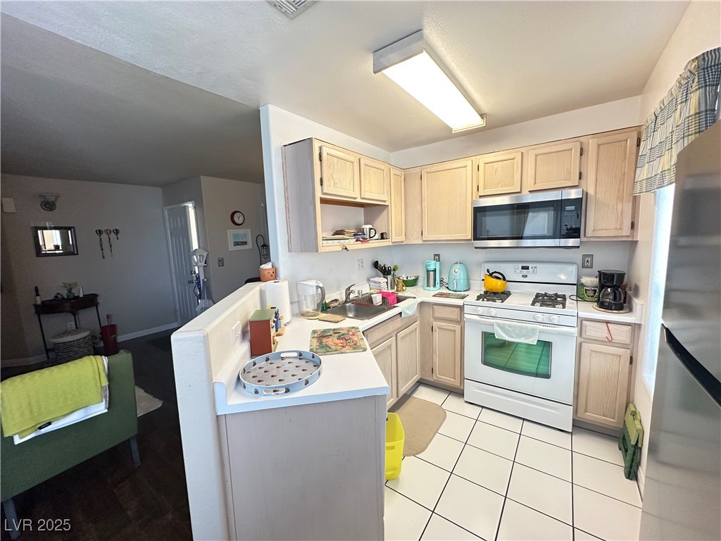 698 South Racetrack Road, Unit 322 Henderson, NV 89015 - Photo 14 of 39 Kitchen with appliances with stainless steel finishes, a sink, light brown cabinets, light countertops, and light tile patterned floors