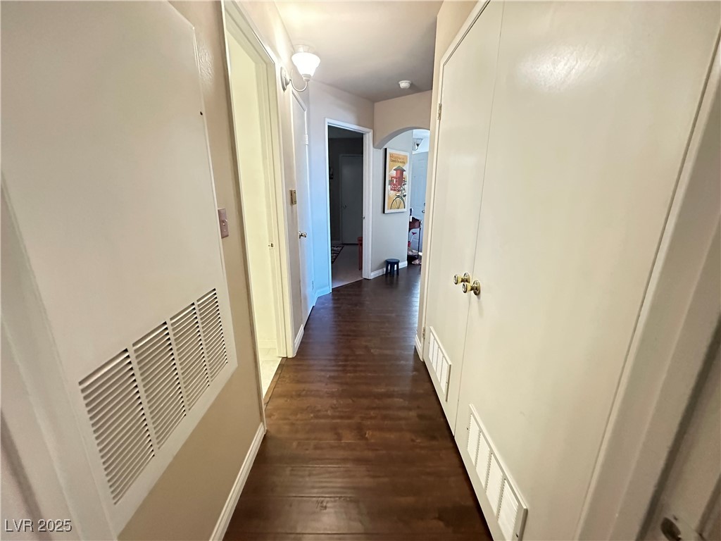 698 South Racetrack Road, Unit 322 Henderson, NV 89015 - Photo 18 of 39 Corridor with arched walkways, a heating unit, baseboards, visible vents, and dark wood-style floors