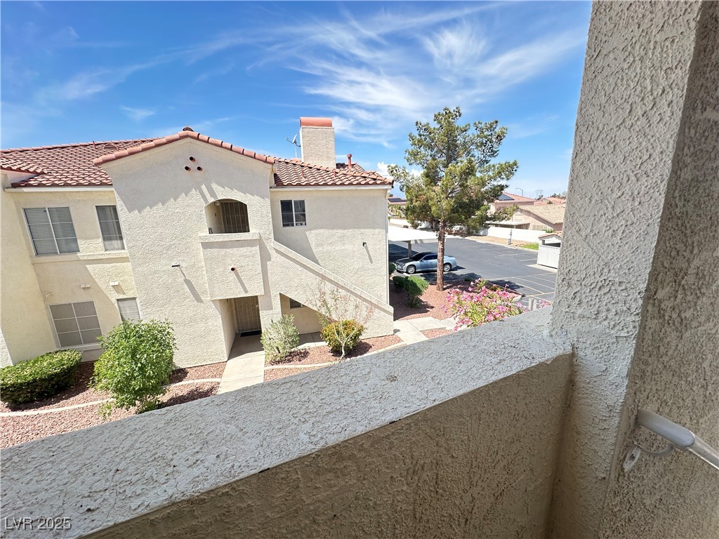 698 South Racetrack Road, Unit 322 Henderson, NV 89015 - Photo 33 of 39 View of property exterior featuring a tiled roof, a chimney, stucco siding, and a balcony
