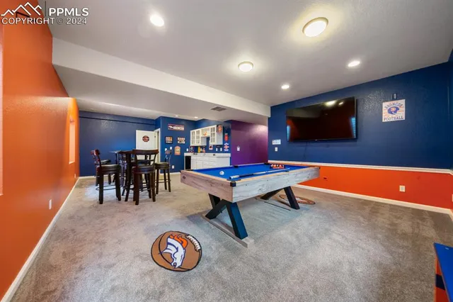 a living room with game table and a flat screen tv