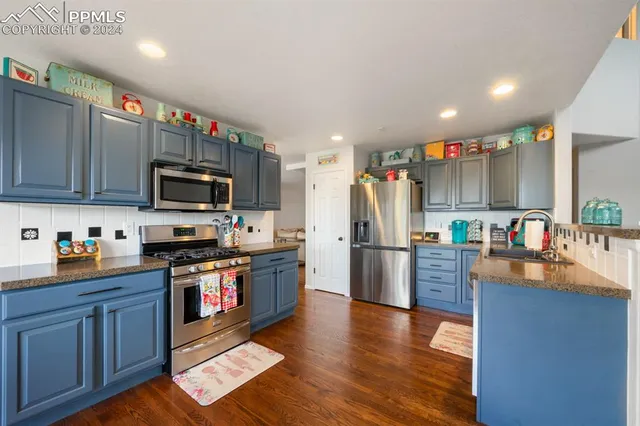 a kitchen with stainless steel appliances granite countertop a refrigerator a stove top oven a sink dishwasher and wooden cabinets with wooden floor